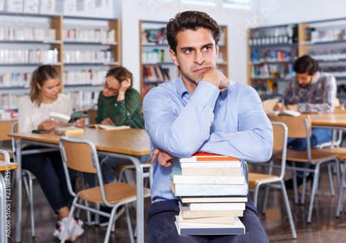 upset man with stack of books in hands