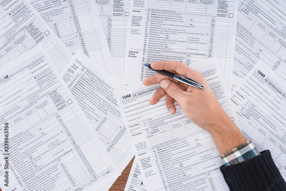 Obraz premium partial view of man holding pen and filling tax forms with copy space