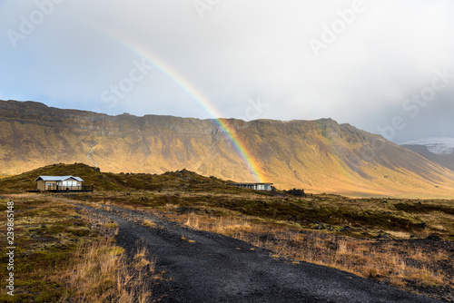 Rainbow over two Cottages on a Lava Field a the Foot of a Mountain in Iceland on a Rainy Day. 