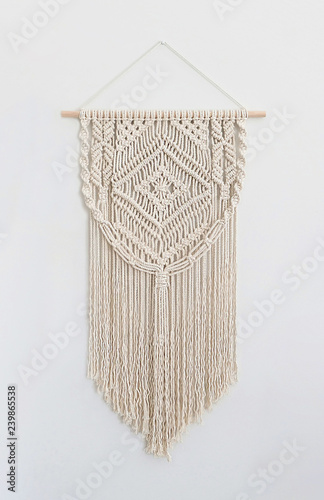 A handmade 100% cotton macrame wall decoration hanging on a white wall. photo