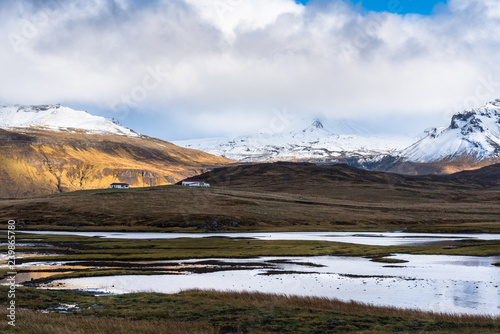 Farm in a Beautiful Mountain Landscape in Iceland on an Autumn Day. A Pond is in Foreground. © alpegor