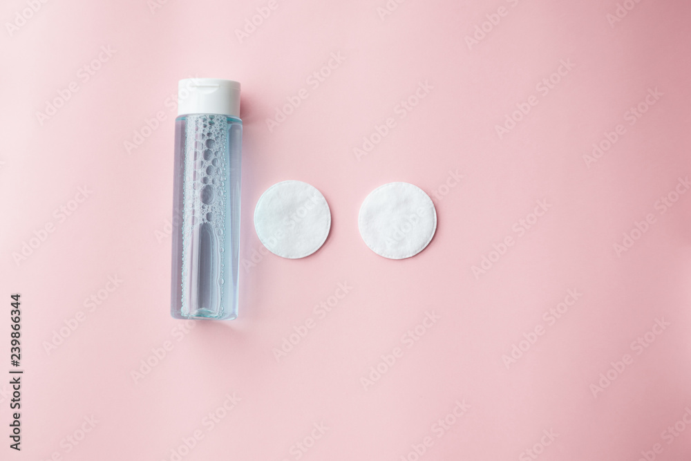 bottle with tonic or micellar cleansing water with fresh herbs and flowers and cotton pads on pink background, top view. Beauty, skin, hair or body care concept. selective focus bottle with tonic or micellar cleansing water with fresh herbs and flowers and cotton pads on pink background, top view. Beauty, skin, hair or body care concept. selective focus