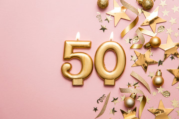 Number 50 gold celebration candle on star and glitter background