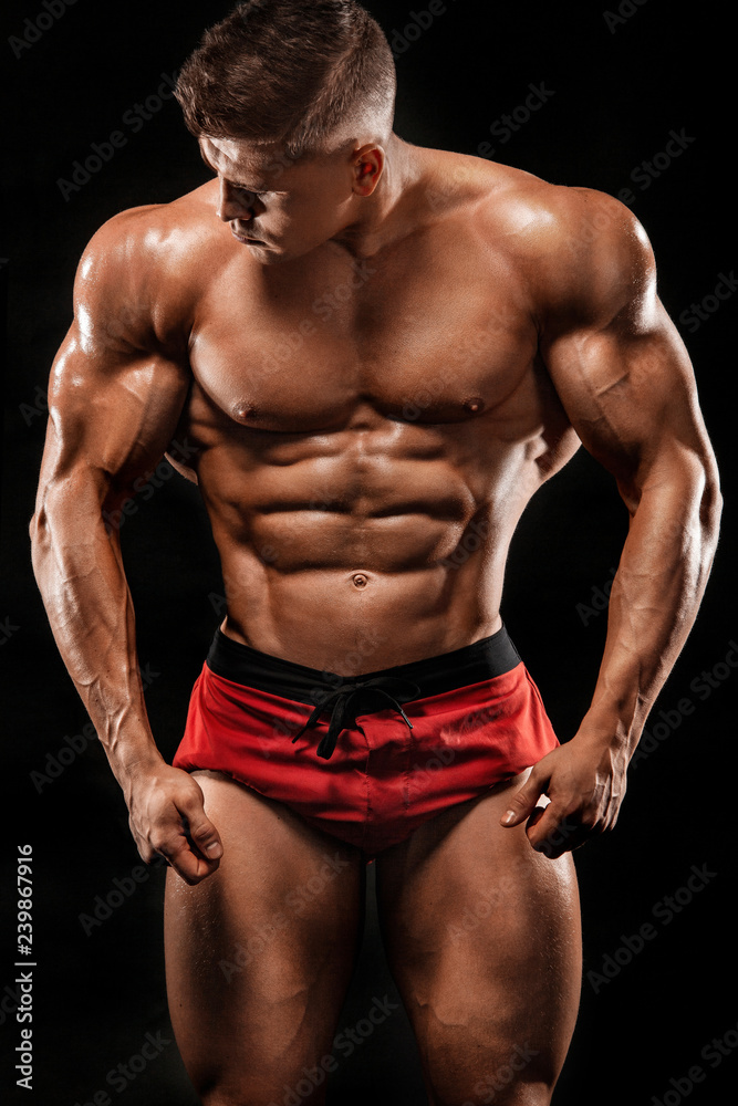 Brutal strong muscular bodybuilder athlete man pumping up muscles on black background. Workout bodybuilding concept. Copy space for sport nutrition ads.