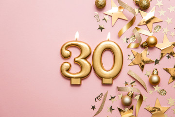 Number 30 gold celebration candle on star and glitter background