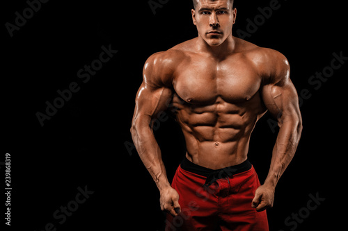 Brutal strong muscular bodybuilder athlete man pumping up muscles on black background. Workout bodybuilding concept. Copy space for sport nutrition ads.