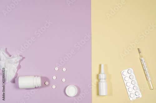 Various medicines, a thermometer, sprays from a stuffy nose and a pain in a throat on a pink background.