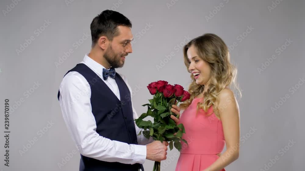 relationships and people concept - happy man giving flowers to woman over grey background relationships and people concept - happy man giving flowers to woman over grey background