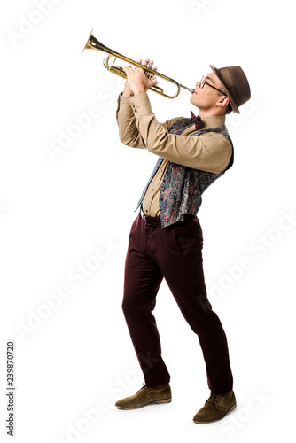 Canvas Print mixed race young man in hat and eyeglasses playing on trumpet isolated on white