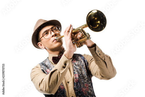 young mixed race man in stylish hat and eyeglasses playing on trumpet isolated on white