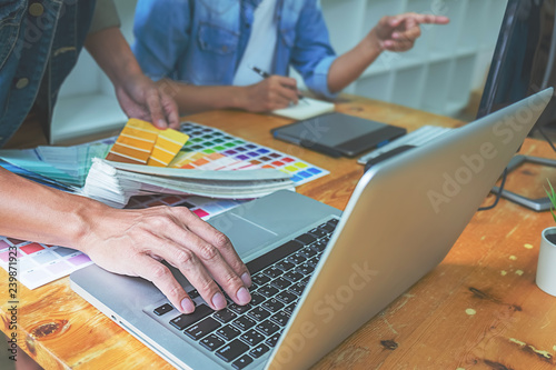 Graphic design with color swatches and tablet on a desk. Graphic designer drawing something on tablet at the office with work tools and accessories.