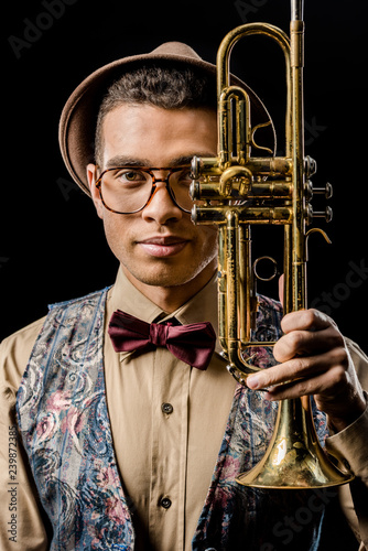 Photography portrait of stylish young male musician posing with trumpet isolated on black