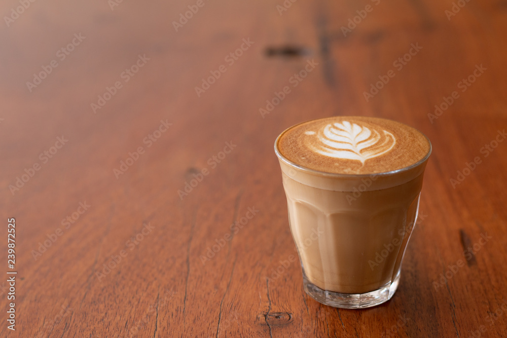 Piccolo Latte art in small glass on wooden desk Piccolo Latte art in small glass on wooden desk