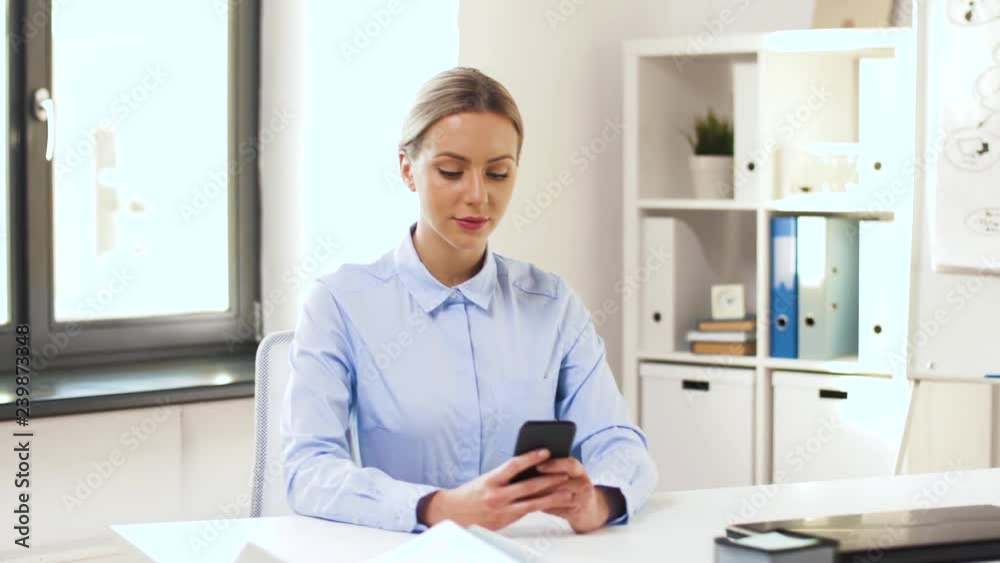 business, technology and people concept - businesswoman with smartphone working at office, shot through glass business, technology and people concept - businesswoman with smartphone working at office, shot through glass