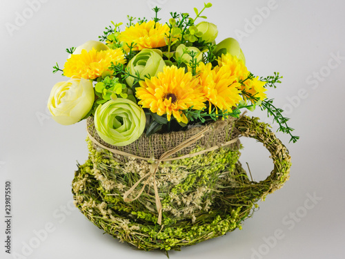 yellow-green bouquet of artificial flowers in a straw pots on a white background