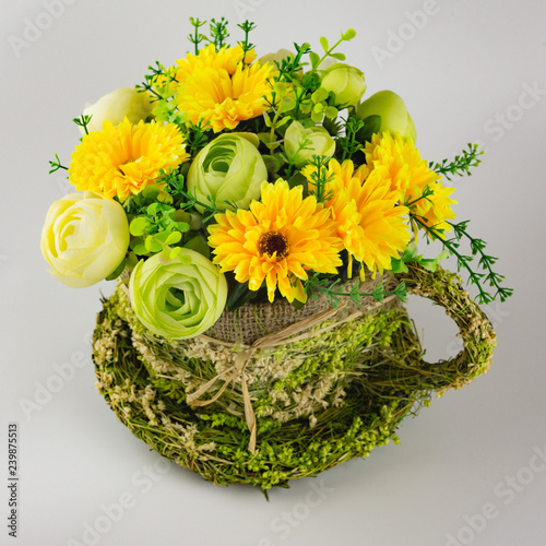 yellow-green bouquet of artificial flowers in a straw pots on a white background