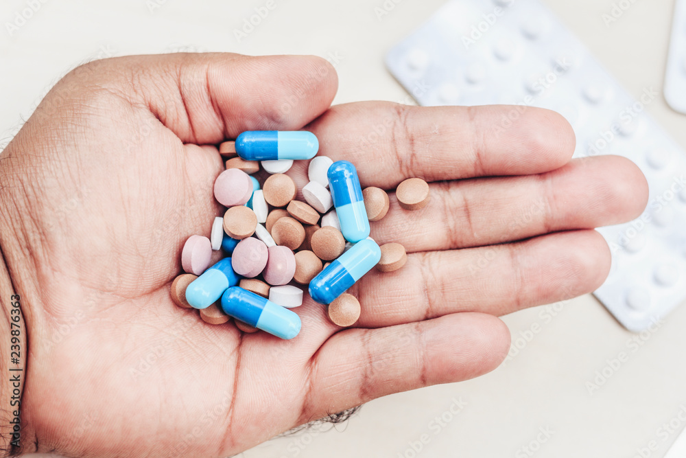 Hand of a man holding several medicine tablets. Hand of a man holding several medicine tablets.