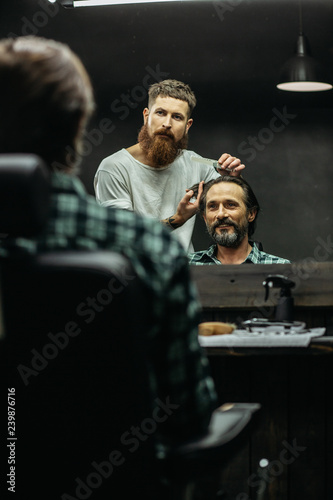 Cheerful man smiling and the barber combing his hair