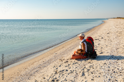 Traveler with the funny dog in his arms relaxes on beach