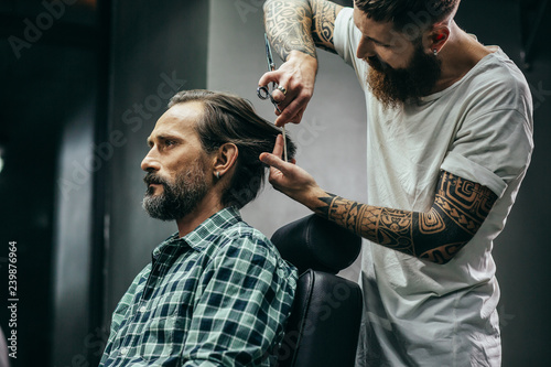 Barbershop visitor looking calm while barber cutting his hair
