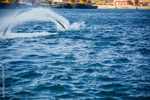 Horizontal View of Santa Claus Diving in the Sea on Flyboard on Blur Background photo