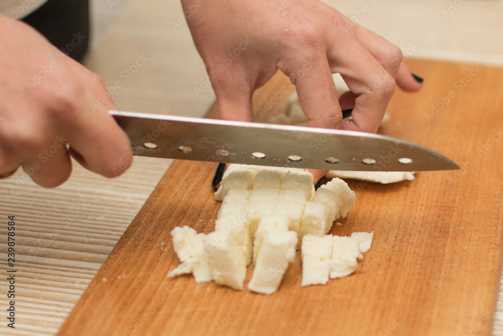 Woman slices cheese on a cutting board.