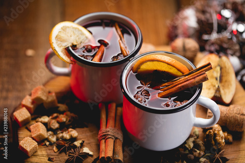 фотографія Hot mulled wine in white rustic mugs with spices and citrus fruit on wooden surface