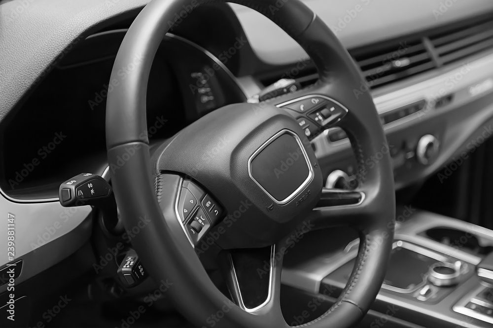 Leather multifunction steering wheel in the cabin of a premium car. Installed under the steering wheel control switches additional functions. Behind the wheel.
