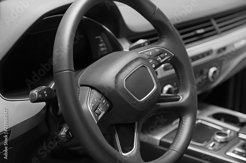 Leather multifunction steering wheel in the cabin of a premium car. Installed under the steering wheel control switches additional functions. Behind the wheel.