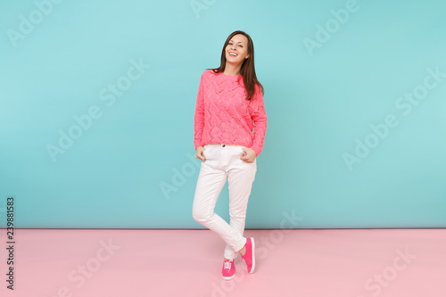Quadro em tela Full length portrait of smiling young woman in knitted rose sweater, white pants posing isolated on bright pink blue pastel wall background in studio