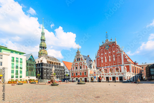 View of the Old Town square, Roland Statue, The Blackheads House near St Peters Cathedral against blue sky in Riga, Latvia. Summer sunny day