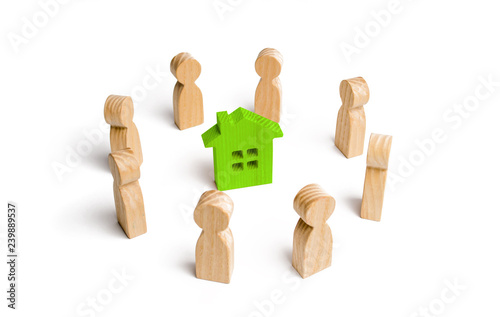 Wooden figurines of people stand around a green house. Search for a new home and real estate. Buying or selling a home. Moving to a new home. Rent or construction. Investments