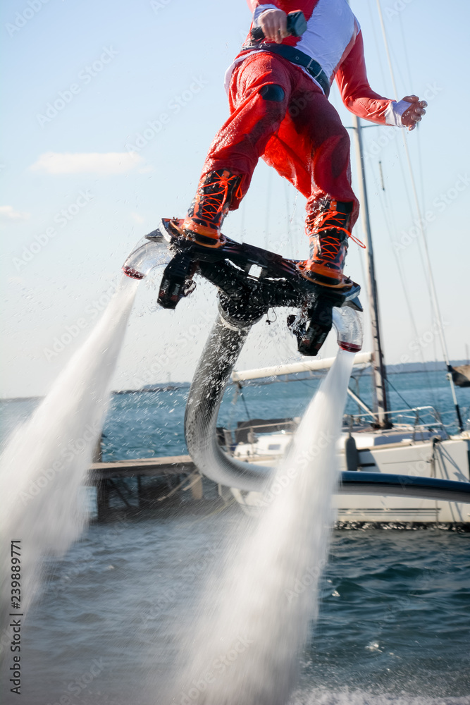 Naklejka premium Vertical View of Santa Claus Flying on Flyboard on Blur Background