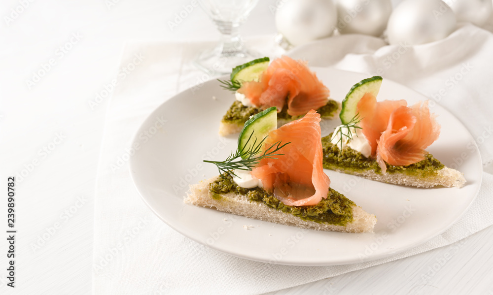 festive canapes with smoked salmon on a plate on a white table with christmas decoration, large copy space festive canapes with smoked salmon on a plate on a white table with christmas decoration, large copy space