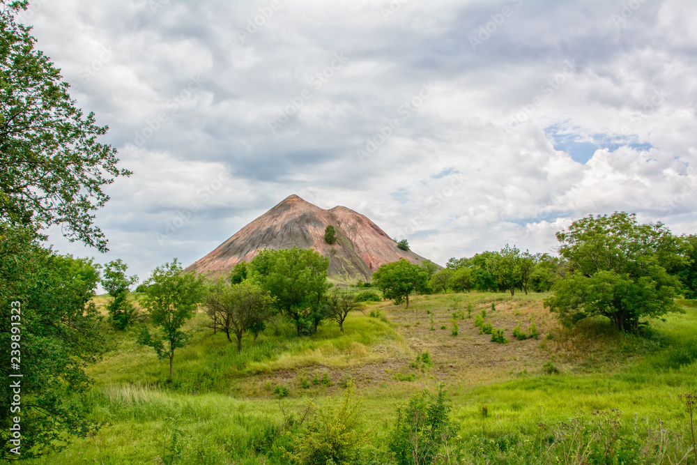the waste heap of the old coal mine in the steppe in Donbass under the cloudy sky