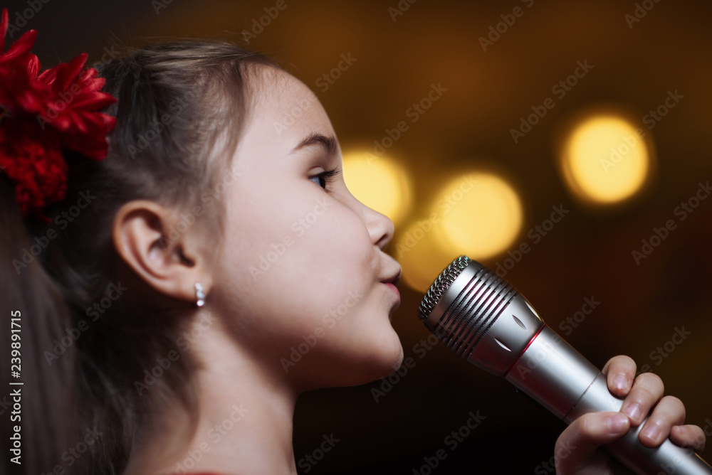 The girl with the microphone. A small child sings karaoke closeup The girl with the microphone. A small child sings karaoke closeup