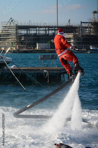 Vertical View of Santa Claus Flying on Flyboard on Blur Background photo