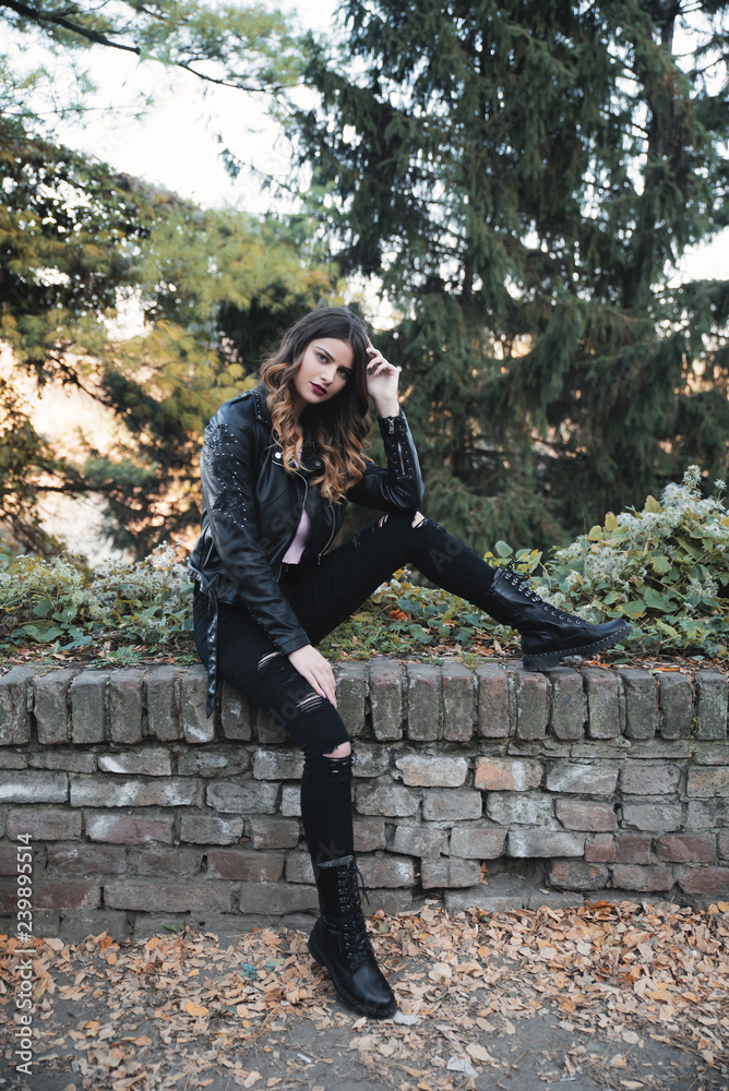 Young woman wearing leather jacket sitting outdoors Young woman wearing leather jacket sitting outdoors