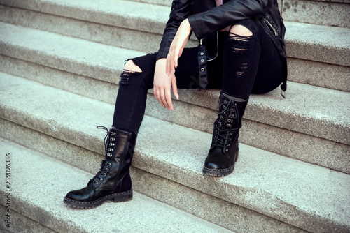 Woman in black boots sitting outdoors