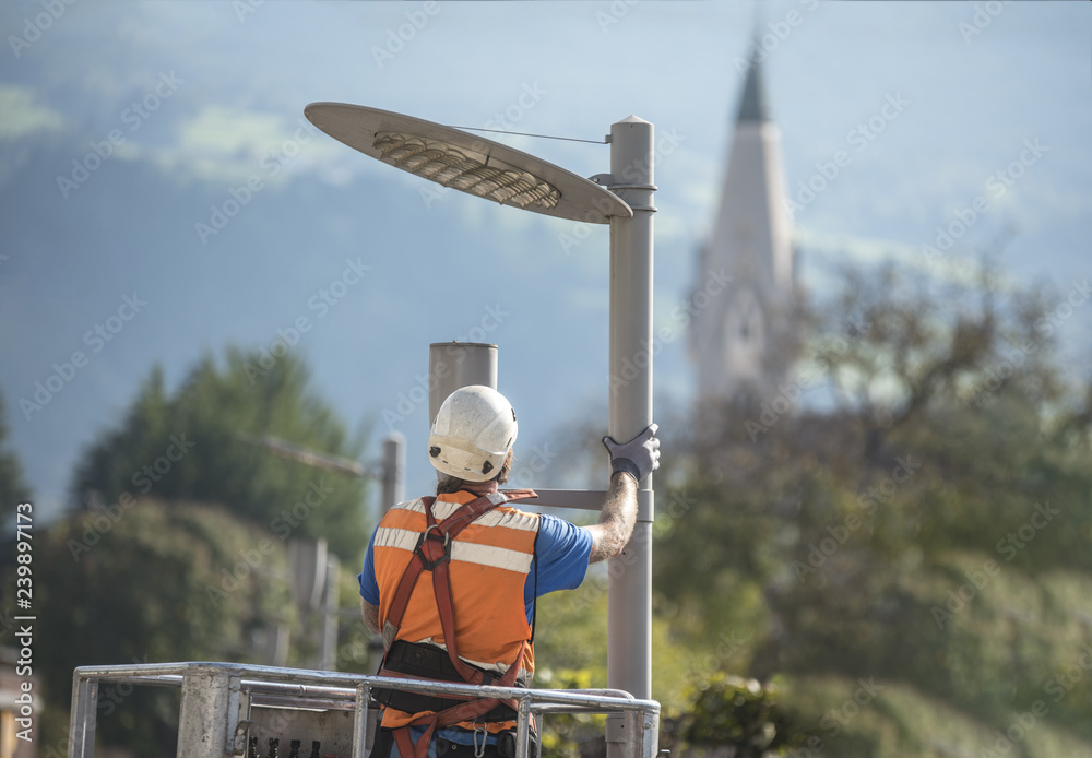 Electric technical worker with helmet and safety protective equipment  installs new led lights. Worker in lift bucket repair light pole.  Modernization of street lamps. Technician on aerial device. Stock-foto |  Adobe Stock