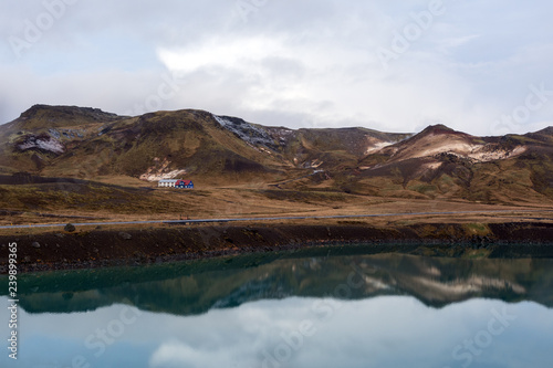 view of house near the lake in abandoned landscape in Iceland, in the background of a snowy mountain