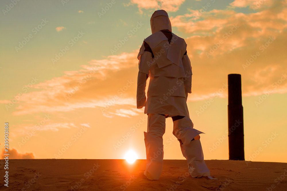 man in the wilderness in a torn spacesuit, walks toward sunset.