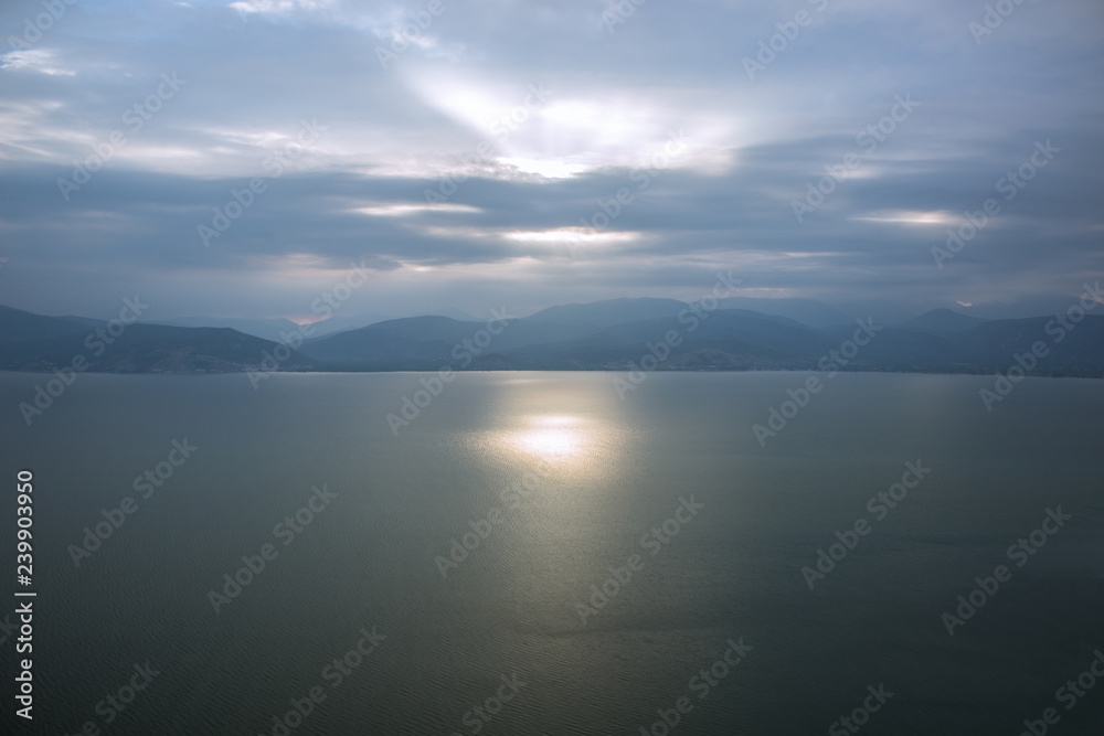 morning sun rise foggy weather scenic time of sea calm water surface and mountain horizon background silhouettes wallpaper pattern concept with empty space for copy or your text