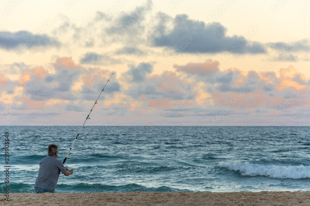 Man alone fishing with a rod in the Campeche Beach, in Florianopolis, Brazil.