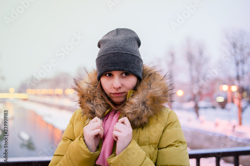 portrait of young woman holding her jacket on the bridge in winter day
