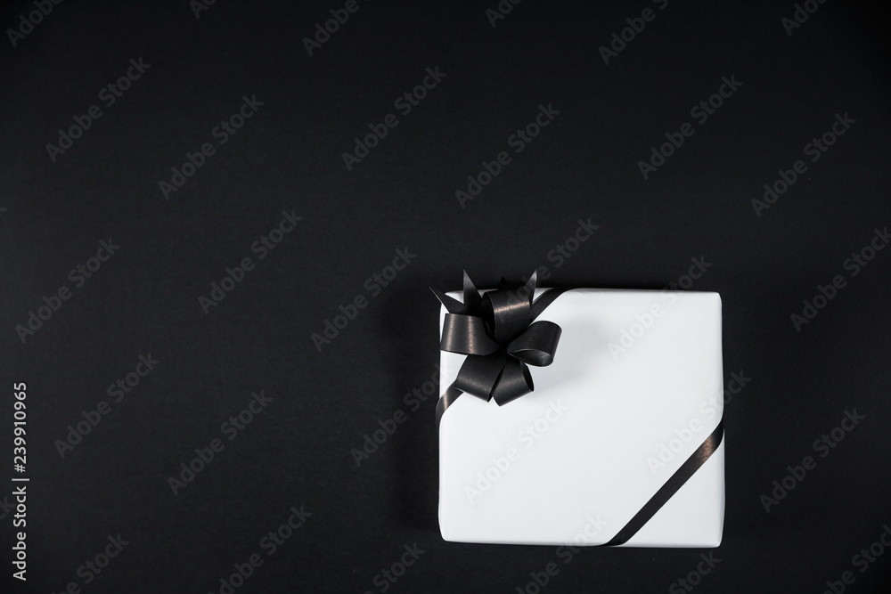 White gift box on a dark contrasted background, decorated with a textured bow, creating a romantic atmosphere.