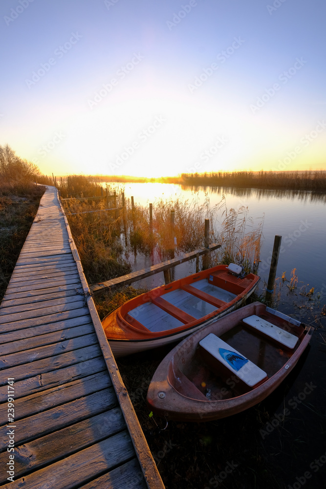two boats at small harbor with wooden bridge and sunrise in backgrounds two boats at small harbor with wooden bridge and sunrise in backgrounds