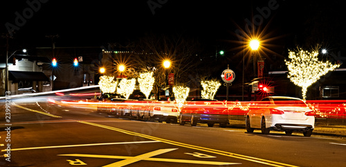 Christmas lights at night with blurred car lights on the street. © Joe