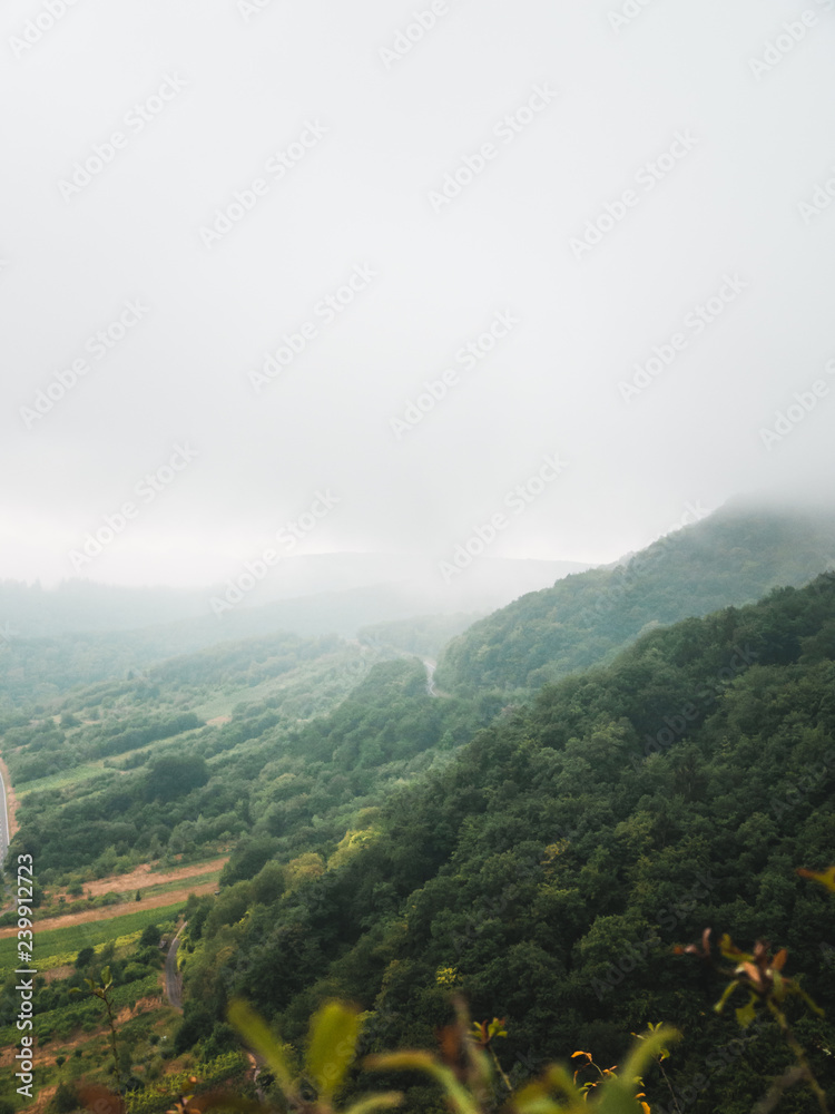 Fototapeta premium Moody landscape: hilly terrain covered in clouds and fog