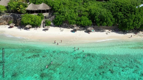 A Small Group of People Enjoying a Perfect Day on a Pristine Tropical Beach in Cura√ßao in the Caribbean Islands, Aerial Approach and Tilt Down Shot photo